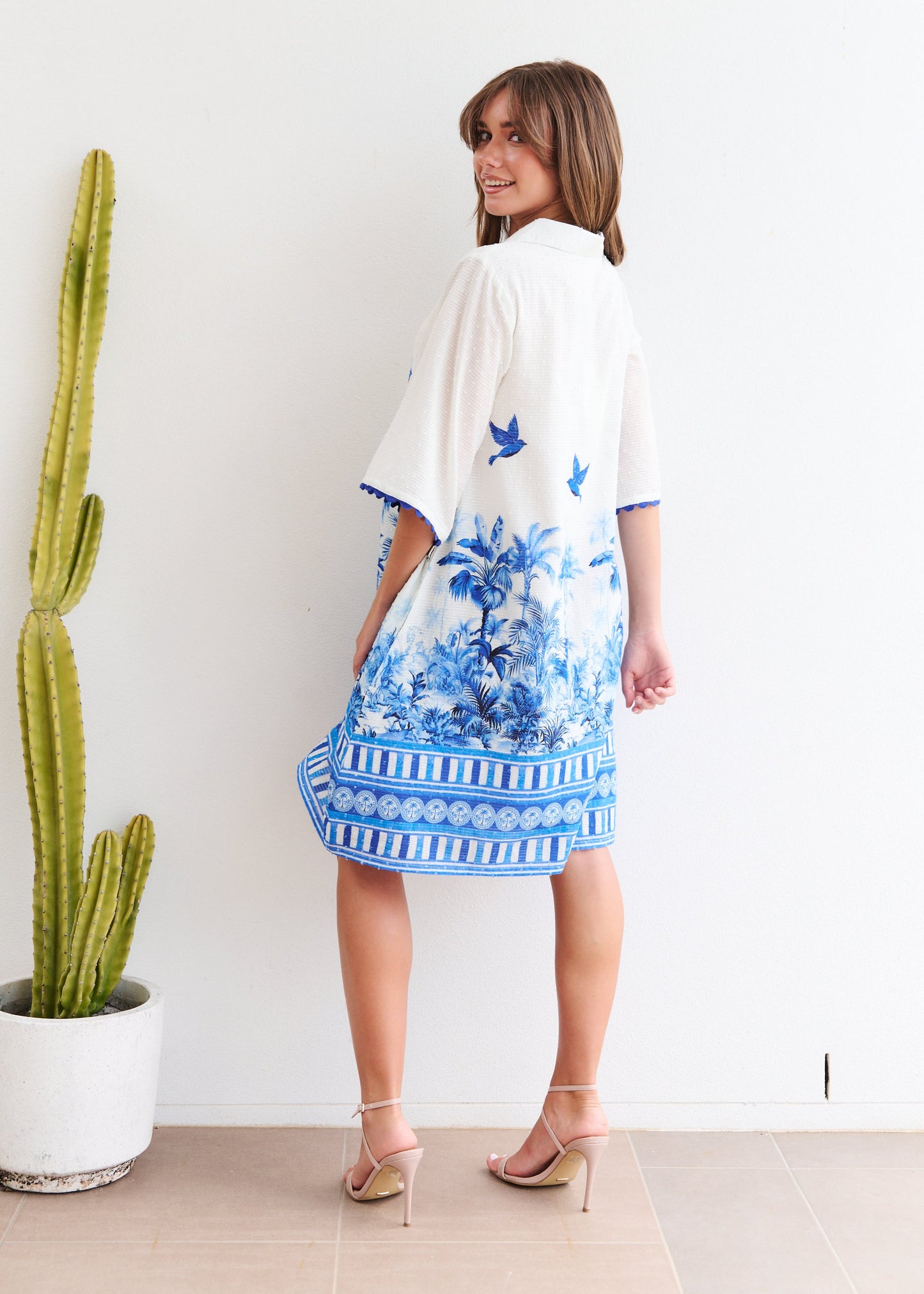 Woman wearing a blue and white floral dress with a cactus plant in the background