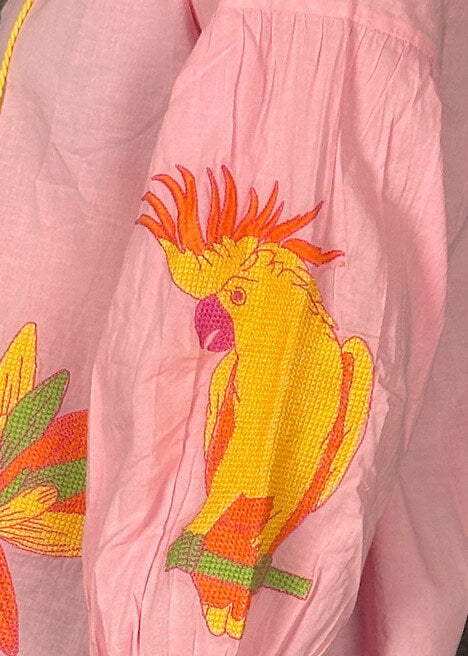 Pink womens top with a colorful parrot embroidery design