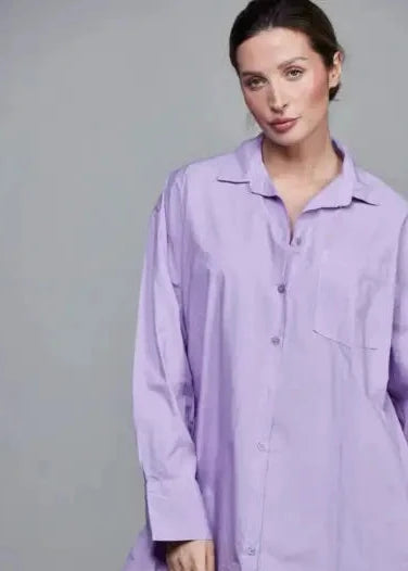 Woman wearing a light purple shirt dress against a gray background