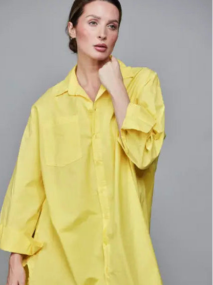 Woman wearing a yellow oversized shirt against a gray background