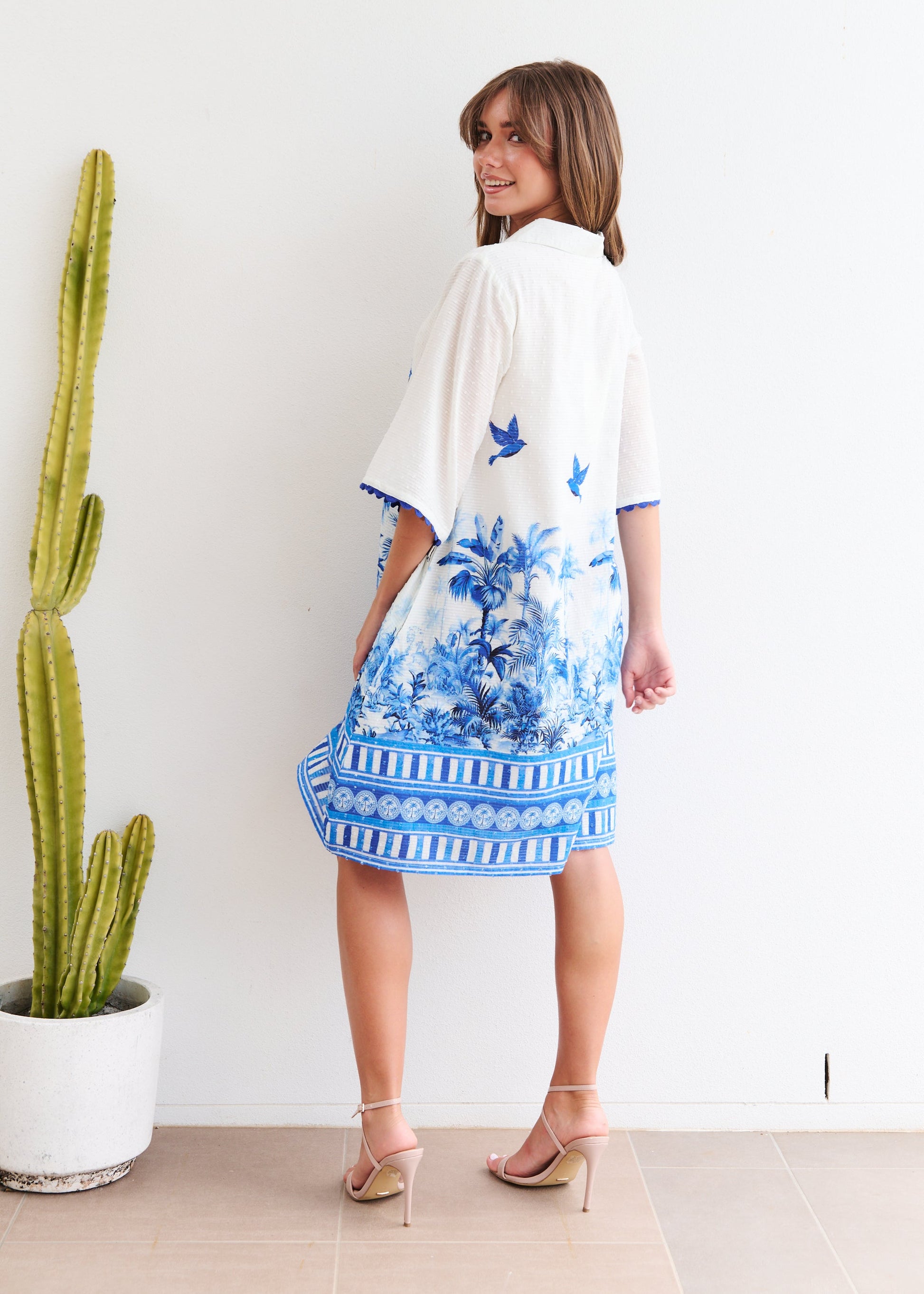 Woman wearing a blue and white floral dress with a cactus plant in the background