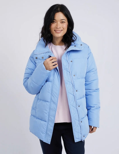 Woman wearing a light blue puffer jacket on a plain background