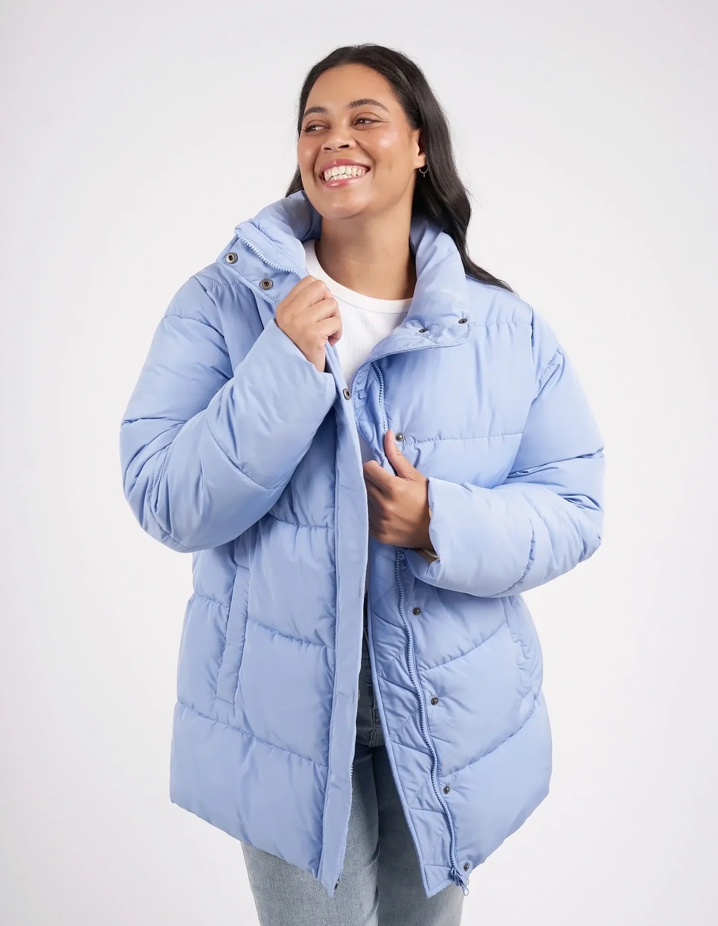 Woman wearing a light blue puffer jacket on a white background