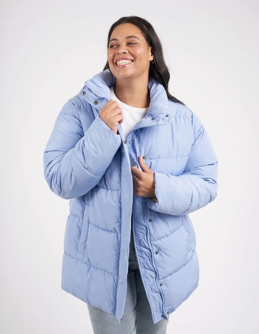 Woman wearing a light blue puffer jacket on a white background