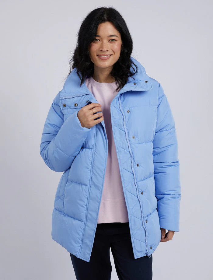 Woman wearing a light blue puffer jacket on a plain background