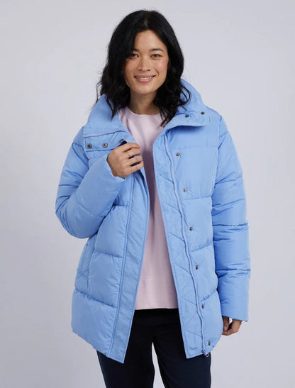 Woman wearing a light blue puffer jacket on a plain background